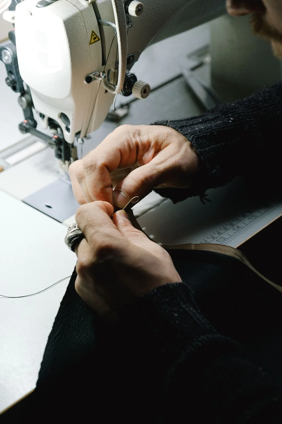 Les mains d’une personne réalisent une couture à la machine.