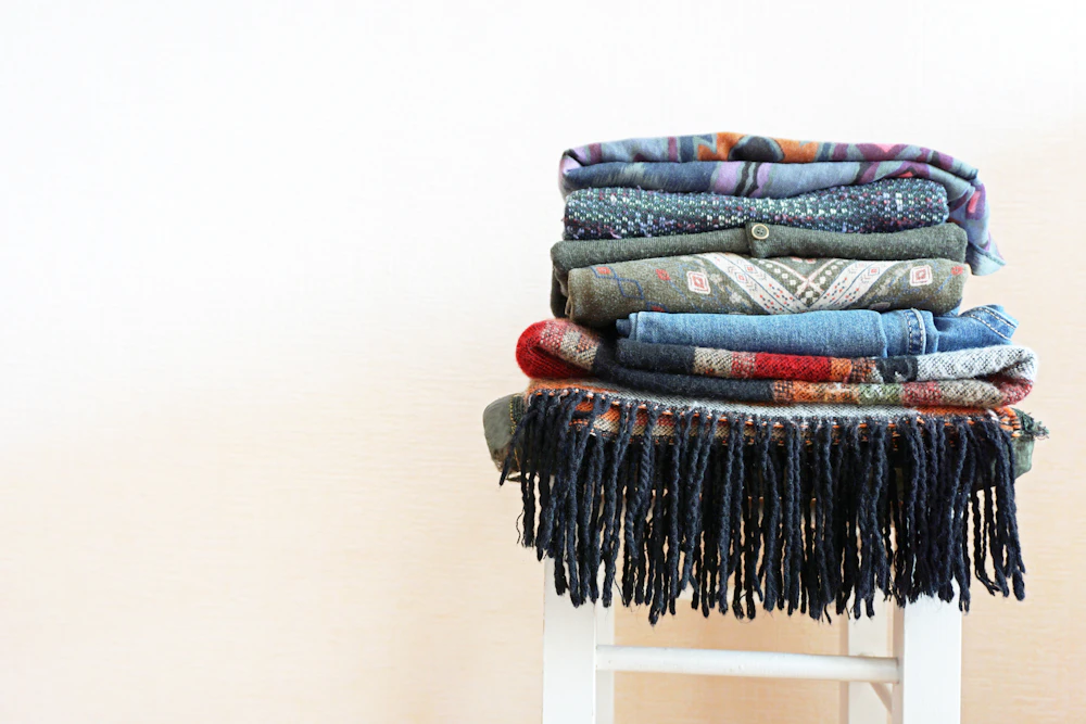 Une pile de vêtements pliés sur un tabouret.
